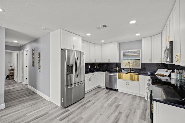 kitchen featuring visible vents, white cabinets, decorative backsplash, light wood-style flooring, and appliances with stainless steel finishes