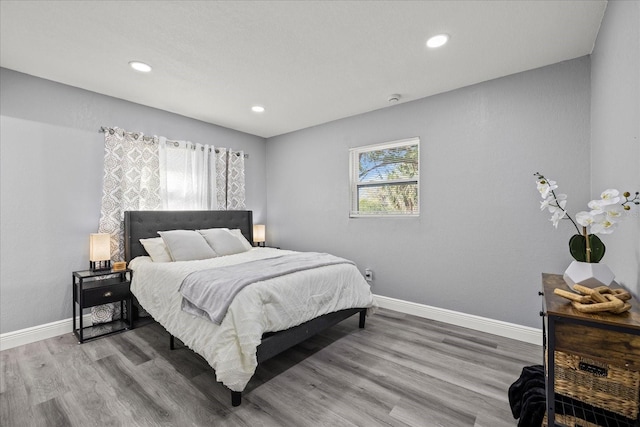 bedroom with baseboards, wood finished floors, and recessed lighting