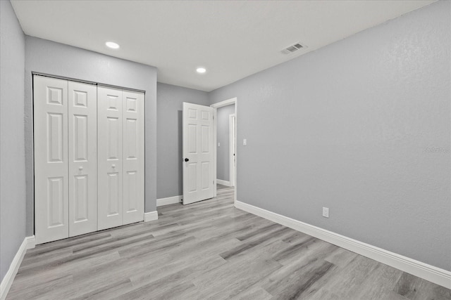 unfurnished bedroom featuring light wood-style flooring, recessed lighting, visible vents, baseboards, and a closet