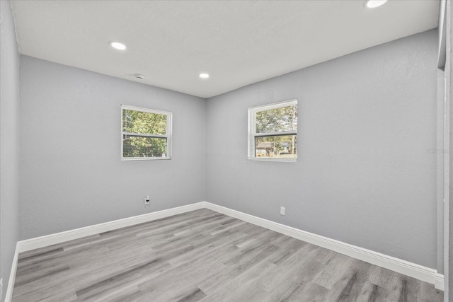 unfurnished room with recessed lighting, plenty of natural light, baseboards, and wood finished floors