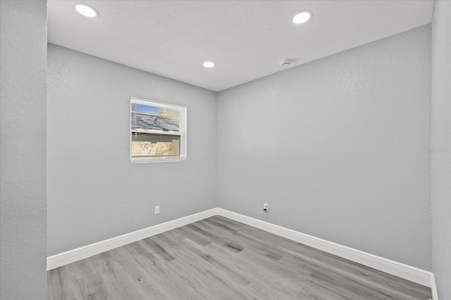 spare room with baseboards, wood finished floors, and recessed lighting