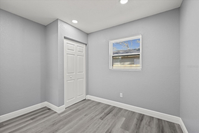 spare room with recessed lighting, light wood-type flooring, and baseboards