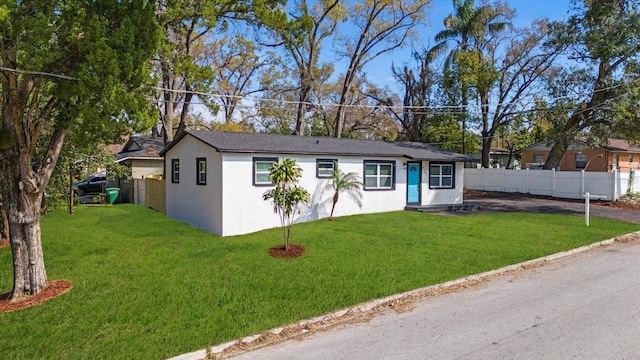 view of front of house with a front yard, fence, and stucco siding