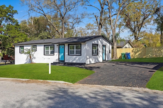 view of front of house featuring aphalt driveway, a front yard, and fence