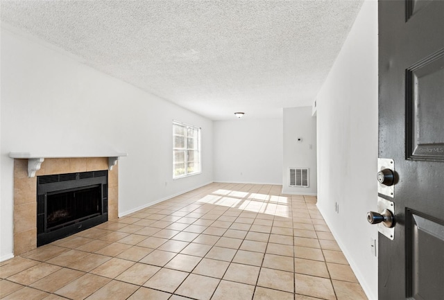 unfurnished living room featuring light tile patterned floors, visible vents, a textured ceiling, and a tile fireplace