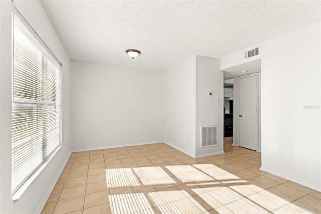 unfurnished room with visible vents, a textured ceiling, and light tile patterned flooring