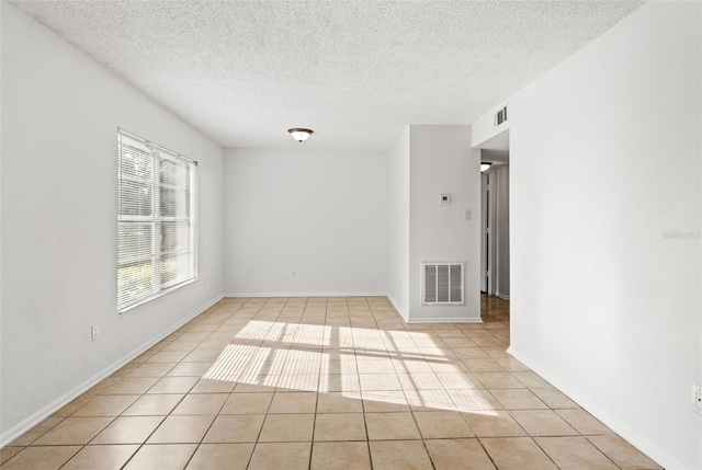 empty room with light tile patterned flooring, visible vents, and a textured ceiling