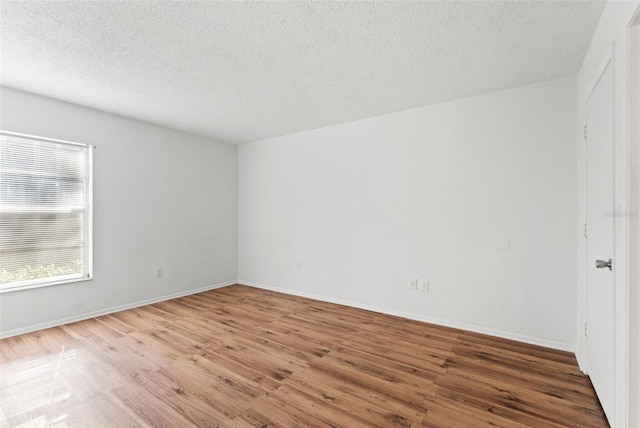 unfurnished room featuring a textured ceiling, baseboards, and wood finished floors