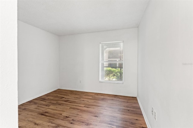 empty room featuring wood finished floors and baseboards