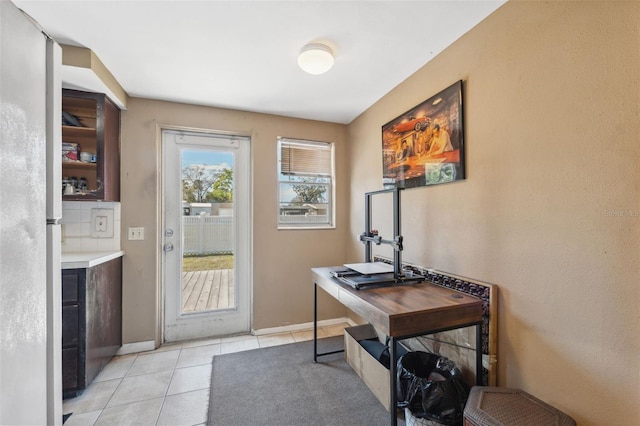 doorway featuring light tile patterned floors and baseboards