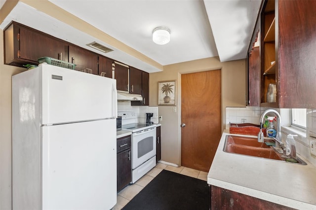 kitchen with backsplash, light tile patterned flooring, a sink, white appliances, and under cabinet range hood