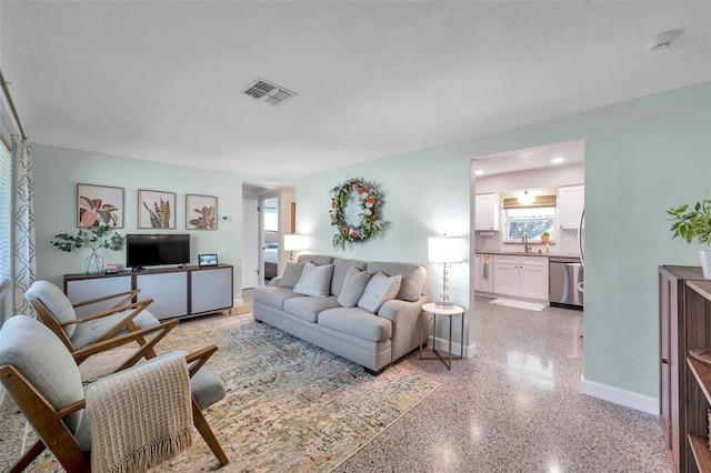 living area featuring light speckled floor, visible vents, and baseboards