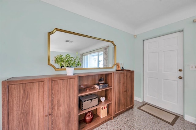 entryway with light speckled floor, visible vents, and baseboards