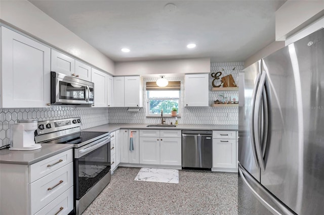 kitchen with stainless steel appliances, a sink, white cabinets, open shelves, and tasteful backsplash