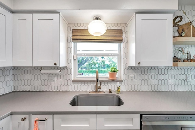 kitchen with a sink, backsplash, white cabinets, and stainless steel dishwasher