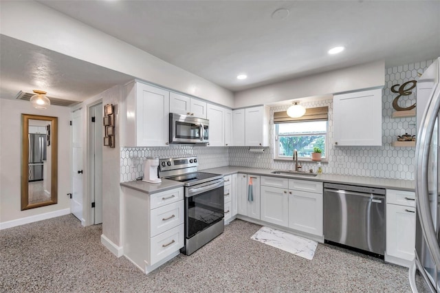 kitchen featuring stainless steel appliances, a sink, white cabinetry, and baseboards