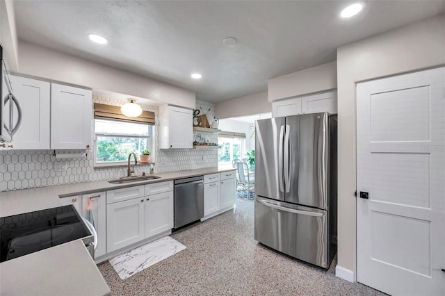 kitchen featuring recessed lighting, stainless steel appliances, a sink, white cabinetry, and decorative backsplash