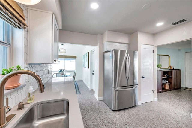 kitchen featuring recessed lighting, visible vents, decorative backsplash, freestanding refrigerator, and a sink