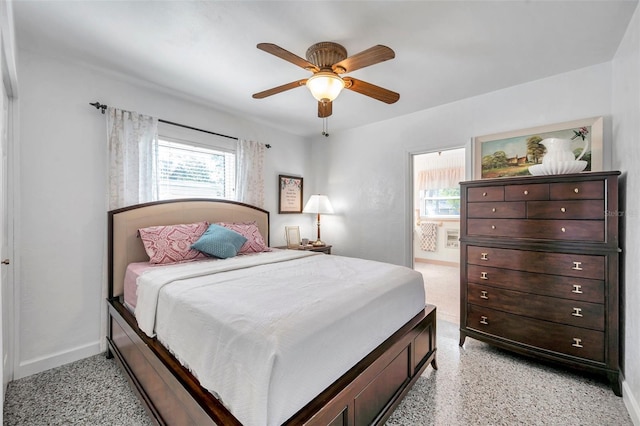 bedroom with ensuite bath, baseboards, light speckled floor, and a ceiling fan