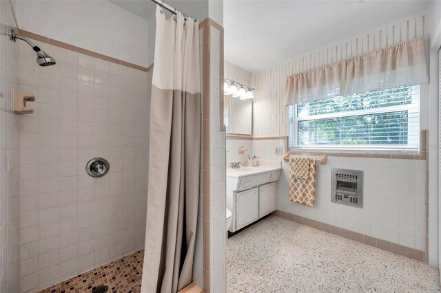 bathroom with a tile shower, heating unit, and speckled floor