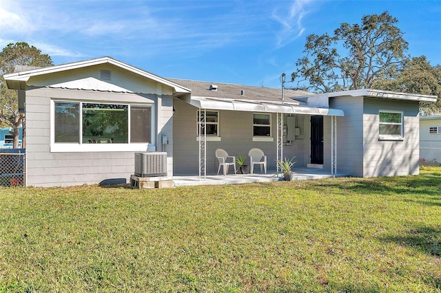 rear view of property featuring cooling unit, a lawn, and fence