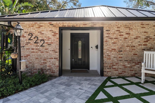 entrance to property featuring metal roof and brick siding