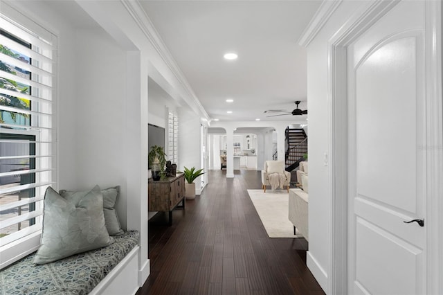 corridor with arched walkways, dark wood finished floors, crown molding, recessed lighting, and stairs