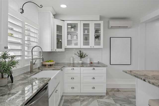 kitchen featuring decorative backsplash, stainless steel dishwasher, glass insert cabinets, an AC wall unit, and white cabinets