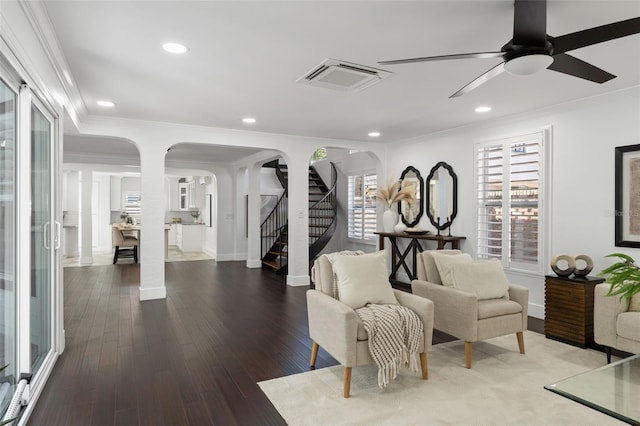 sitting room featuring visible vents, arched walkways, wood finished floors, stairs, and crown molding