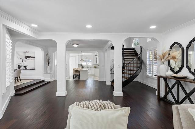 foyer entrance with arched walkways, dark wood finished floors, ornamental molding, baseboards, and stairs