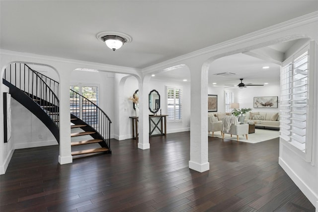 entryway with arched walkways, stairway, dark wood-type flooring, ornamental molding, and baseboards