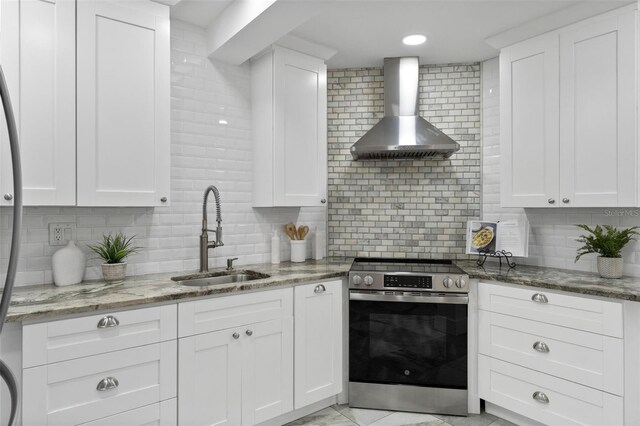 kitchen with wall chimney exhaust hood, electric range, a sink, and white cabinets