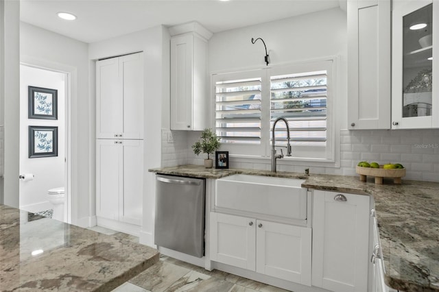 kitchen featuring dishwasher, tasteful backsplash, a sink, and white cabinets