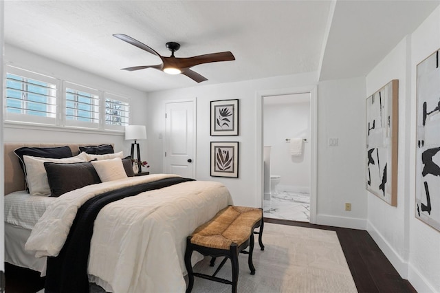 bedroom featuring dark wood-type flooring, ensuite bath, a ceiling fan, and baseboards