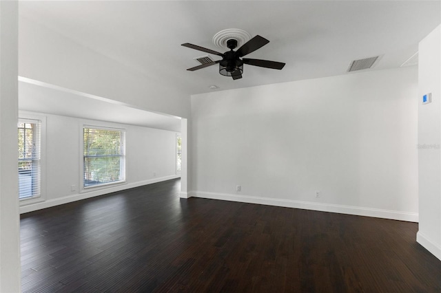 spare room with dark wood-style floors, ceiling fan, visible vents, and baseboards