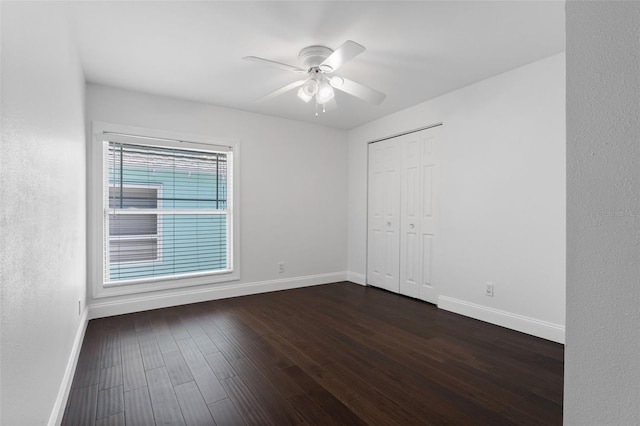 unfurnished bedroom featuring a ceiling fan, a closet, dark wood finished floors, and baseboards