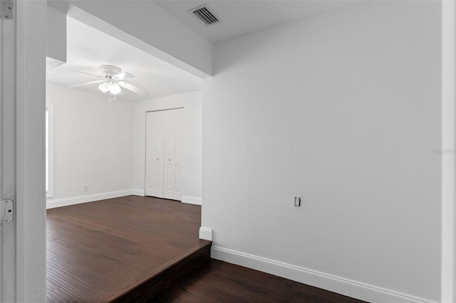 unfurnished room featuring dark wood-type flooring, visible vents, ceiling fan, and baseboards