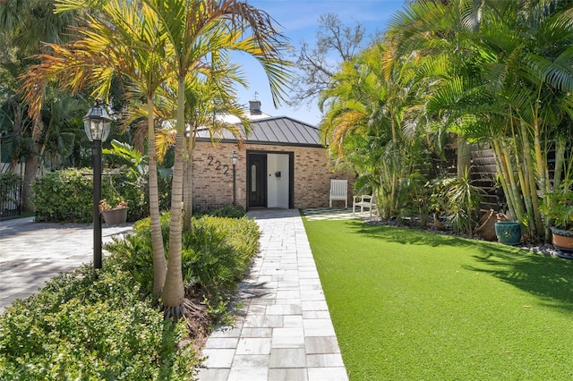 exterior space with metal roof, brick siding, a standing seam roof, and a front yard