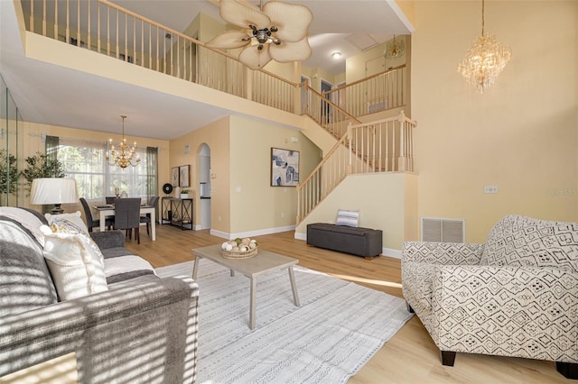 living room with stairs, visible vents, baseboards, and wood finished floors