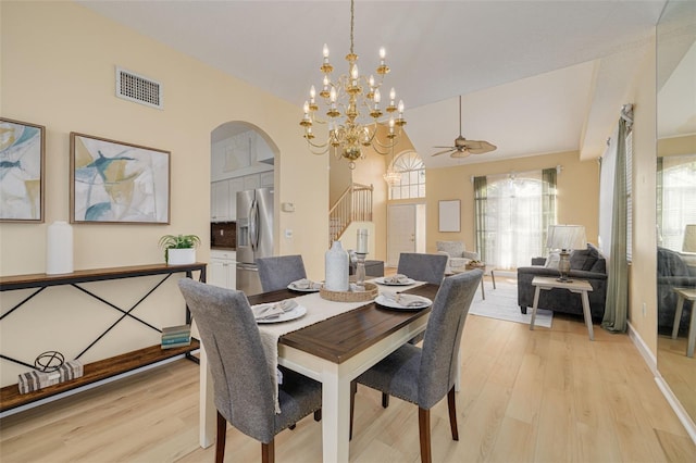 dining room featuring baseboards, visible vents, arched walkways, stairs, and light wood-type flooring