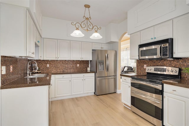 kitchen featuring dark countertops, appliances with stainless steel finishes, backsplash, and a sink