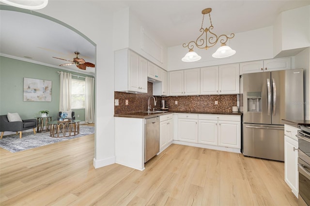 kitchen featuring white cabinets, appliances with stainless steel finishes, light wood-type flooring, decorative backsplash, and dark countertops