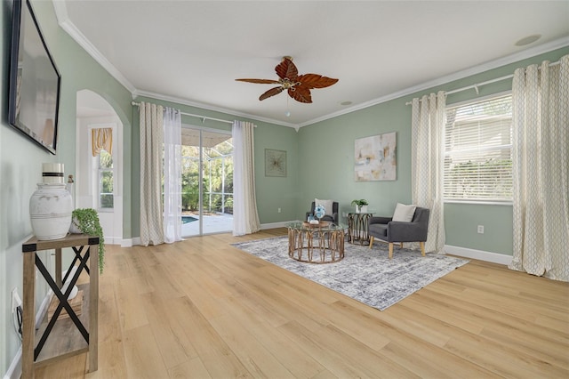 sitting room with ornamental molding, a ceiling fan, baseboards, and wood finished floors