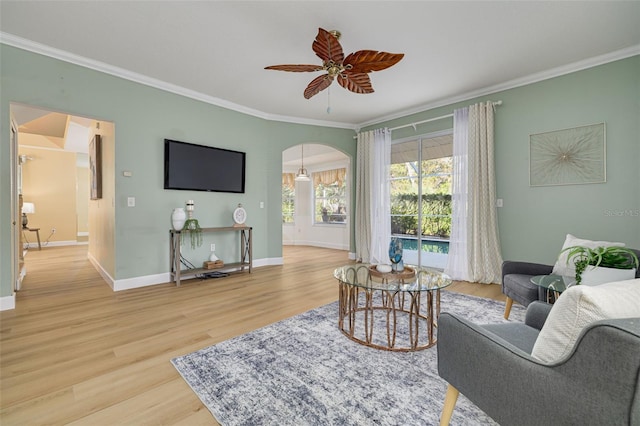 living area with baseboards, arched walkways, wood finished floors, and ornamental molding