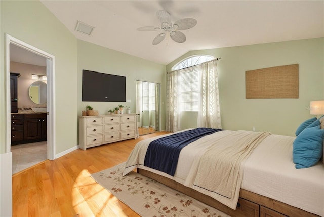 bedroom featuring baseboards, lofted ceiling, ceiling fan, ensuite bathroom, and light wood-style floors