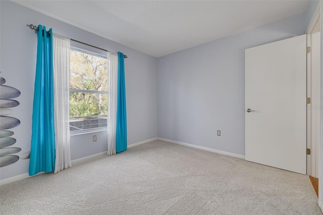 carpeted empty room featuring baseboards