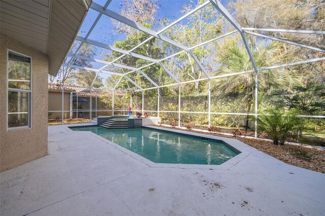 view of pool with a pool with connected hot tub, a patio area, and a lanai