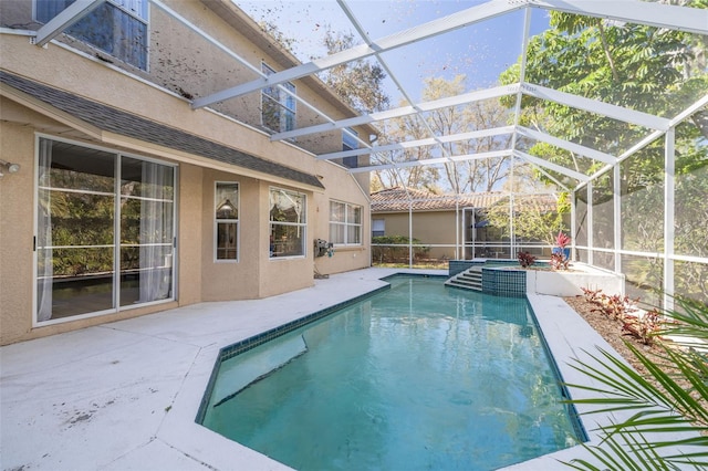 pool featuring glass enclosure and a patio