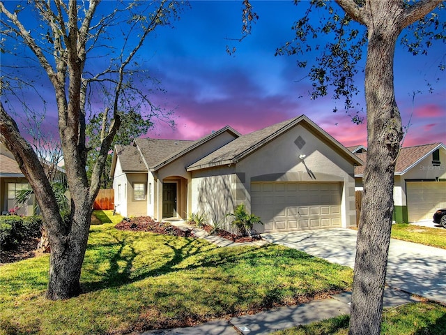 ranch-style home featuring a garage, driveway, fence, a yard, and stucco siding