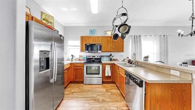kitchen featuring light wood finished floors, stainless steel appliances, light countertops, ornamental molding, and a sink